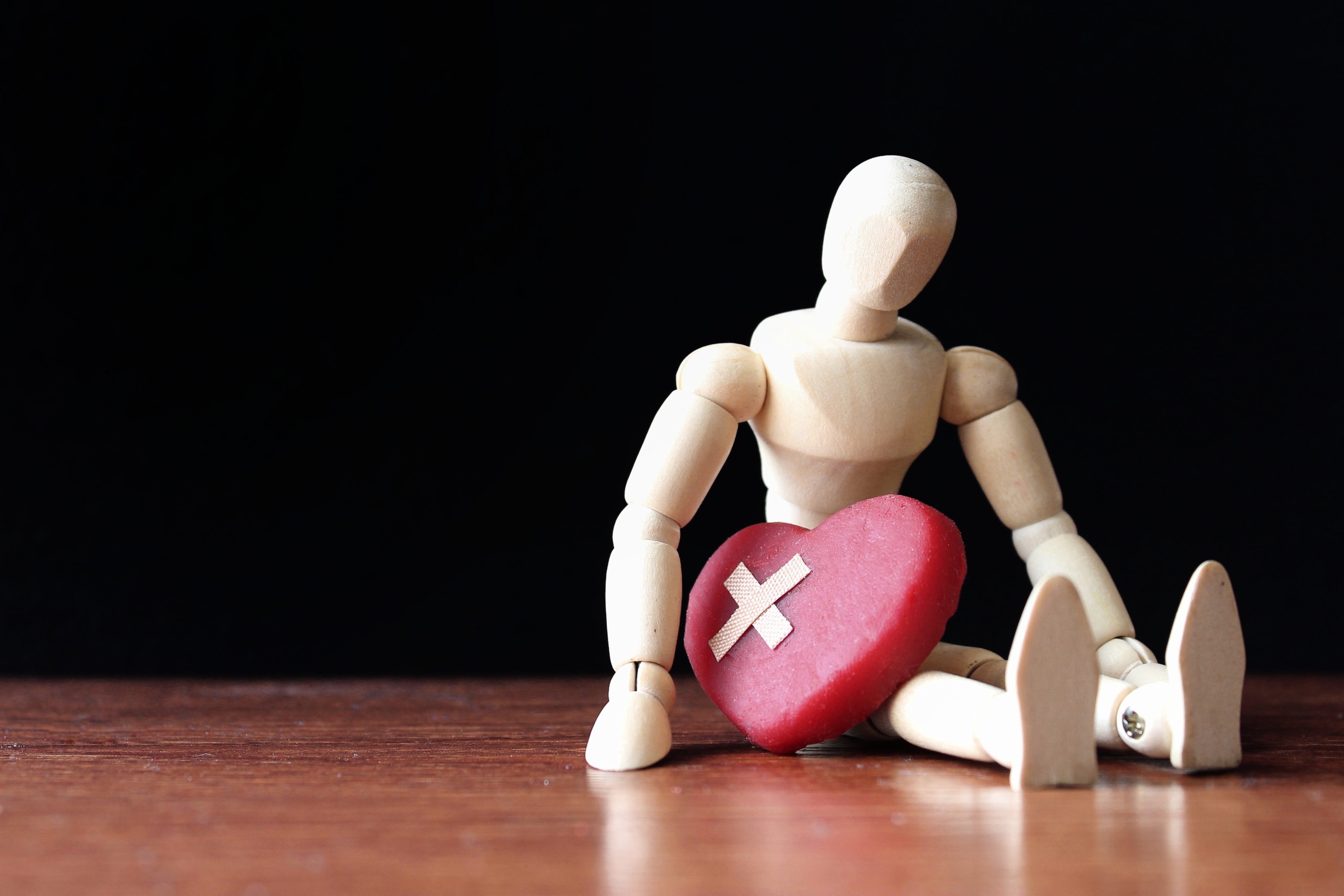 Wooden figure with a heart with a bandaid